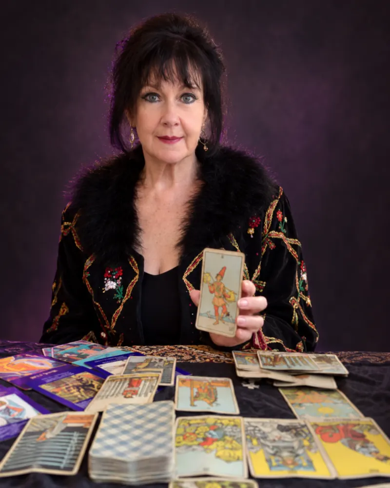 Norma Solazar sosteniendo una carta de tarot frente a una mesa con cartas.